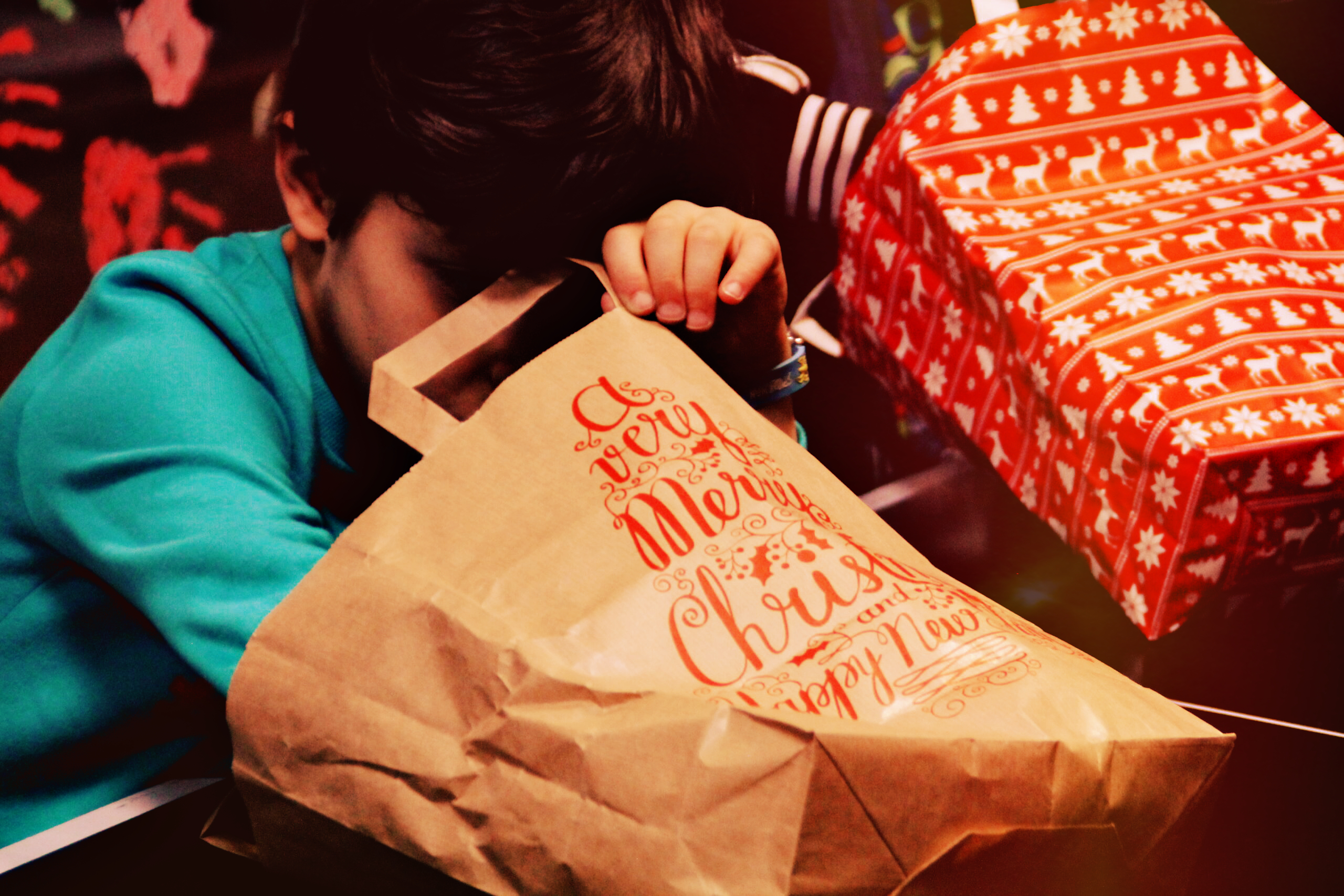 Ein Junge guckt und greift in eine Geschenktüte, die auf dem Tisch liegt.